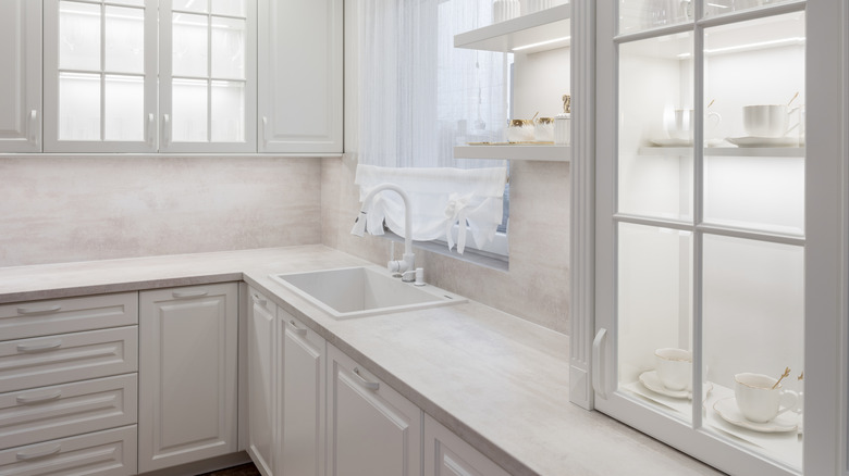 White kitchen with clear glass door cabinet full of dishes