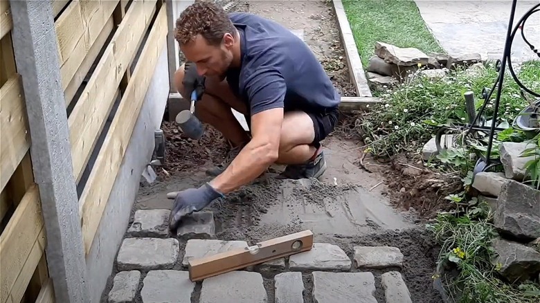 man laying a cobblestone path