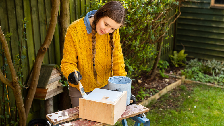 woman painting birdhouse light blue