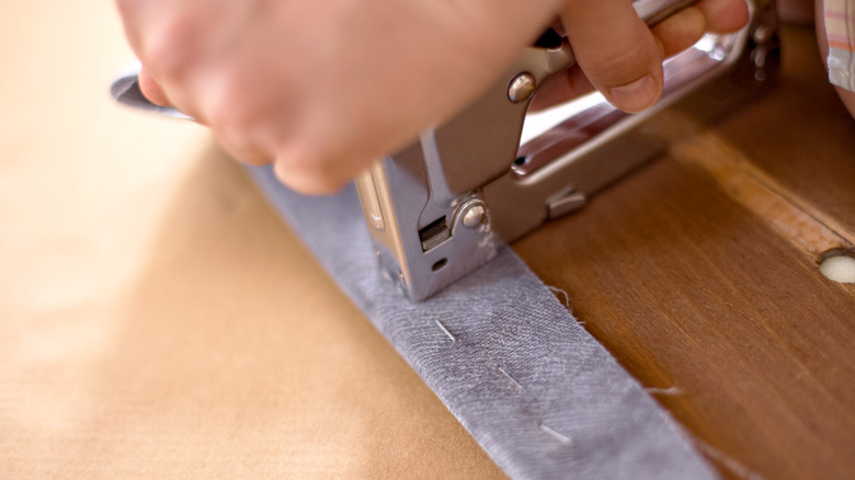 Close up of stapling fabric to a board.