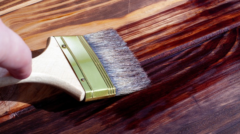 staining wooden board with paintbrush