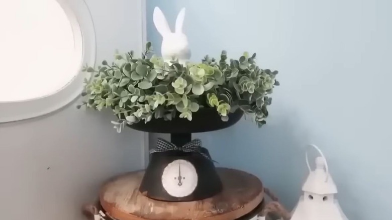 The black faux kitchen scale decorated with greenery and a decorative bunny statue on the top