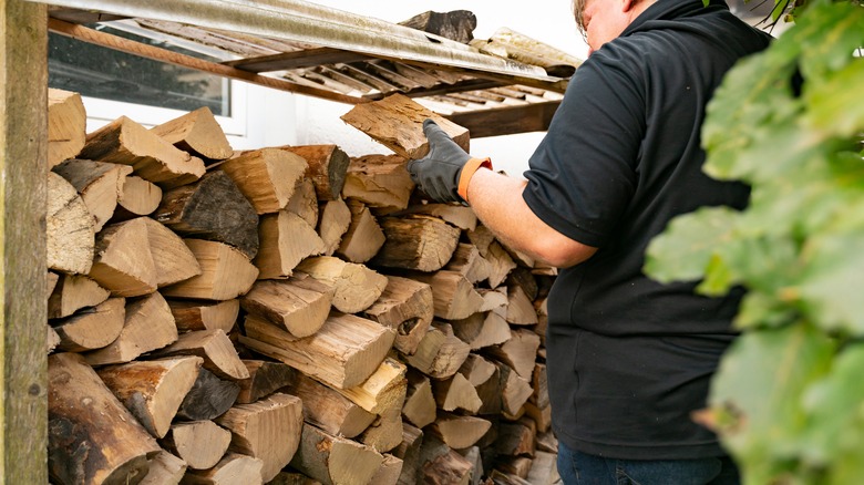 person refilling firewood storage