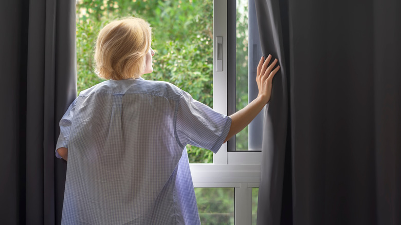 Woman opening blackout drapes