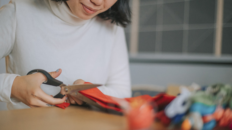 person cutting orange fabric