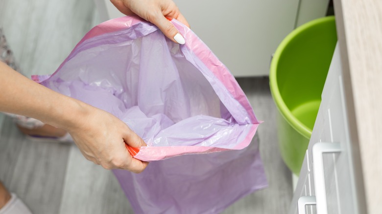 Woman unfolding pink trash bag