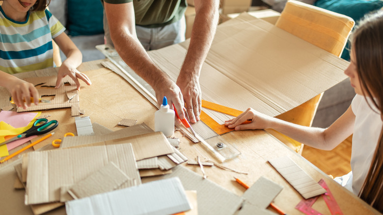 man and kids cutting cardboard