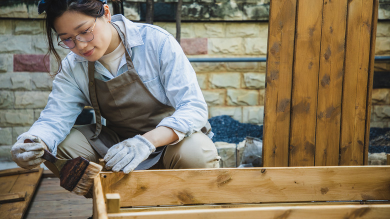 woman staining wood outside