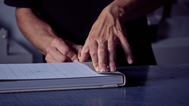 Hands are shone creating a book binding made from fabric