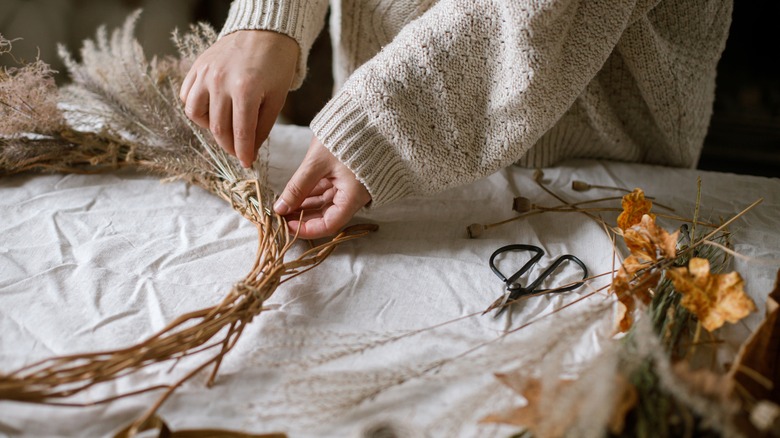 person making wreath from leaves