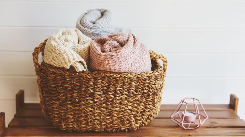 A small basket holds rolled blankets next to a decorative candle