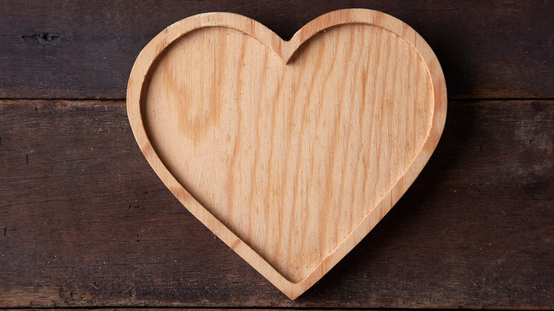 wooden heart-shaped tray with rim on dark wood background