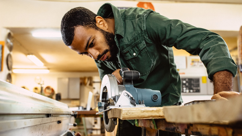 Man cutting wood using a saw.