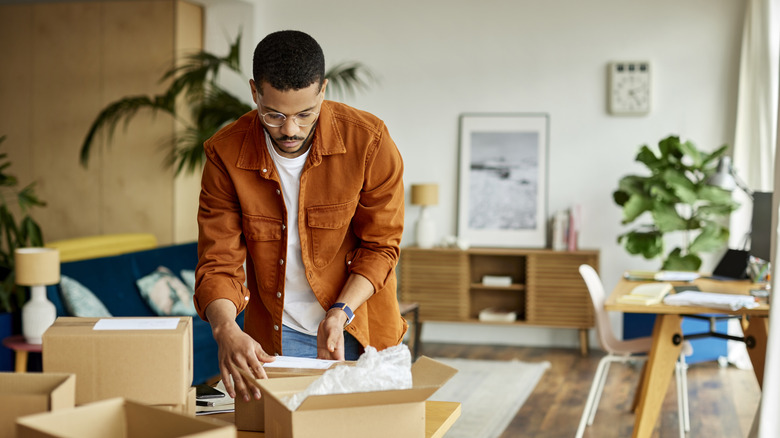 Man looking at cardboard boxes in living room