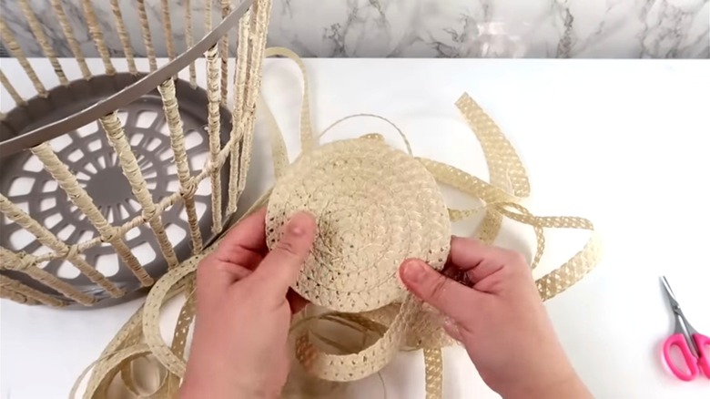person wrapping basket in raffia