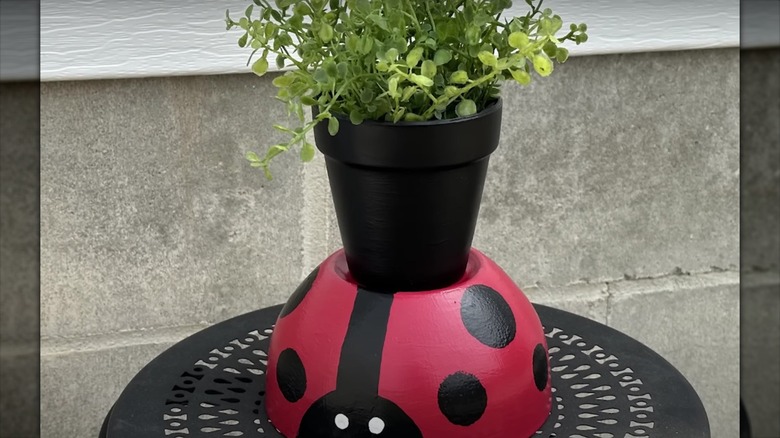 A bowl has been repurposed into a plant stand, and is painted to look like a ladybug.