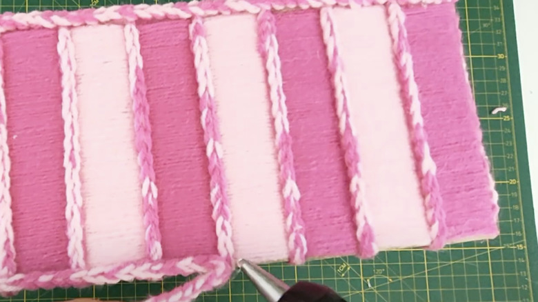 A basket made from toilet paper rolls wrapped in light and dark pink yarn.