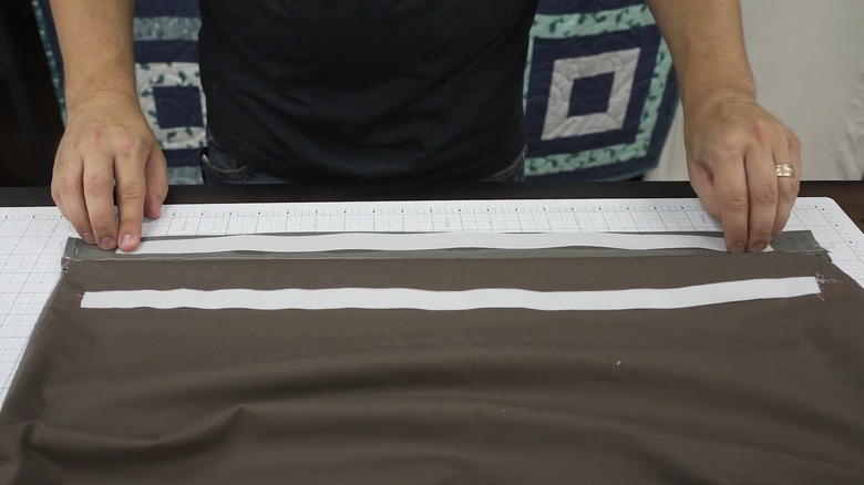 Male hands applying a velcro strip to a cover for the DIY ironing board