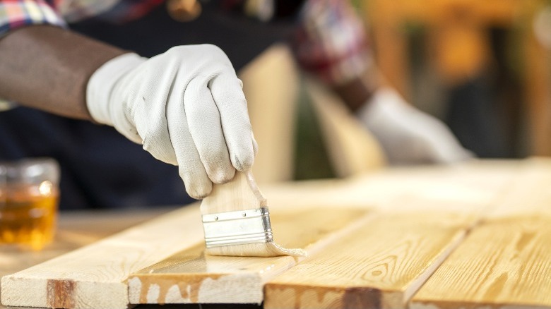 man staining wood boards