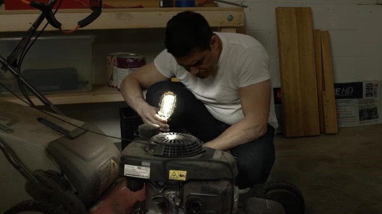 man using work light with lawn mower repair