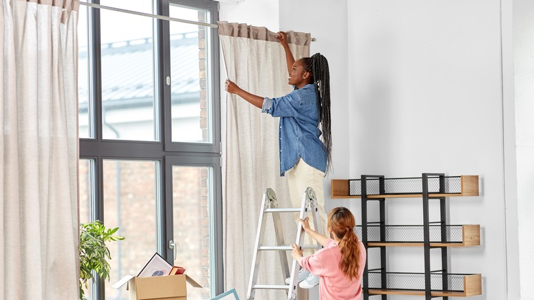 two people hanging curtains