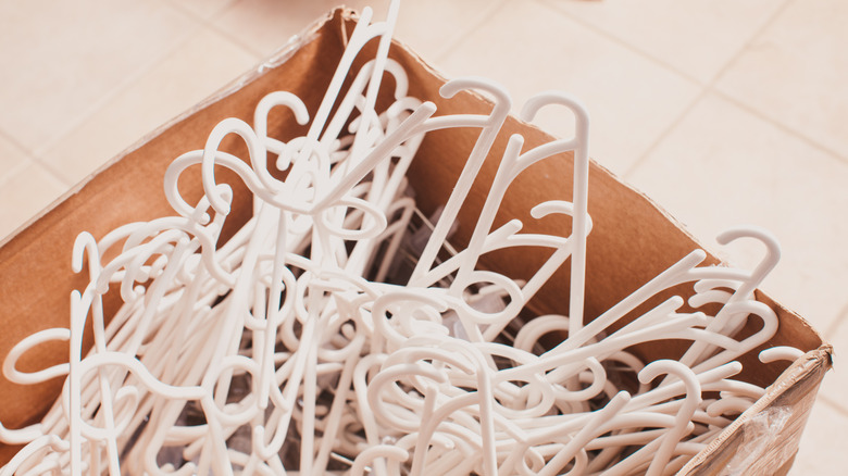 Many white plastic clothes hangers in a large box