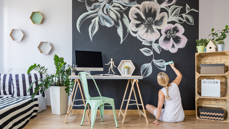 woman drawing on chalkboard wall