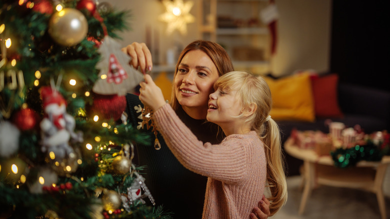 Woman and child hanging ornaments on a Christmas tree