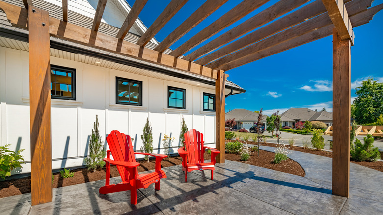 Two chairs sitting in the sun under a backyard pergola