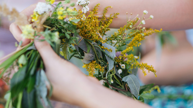 Person holding flowers and greenery