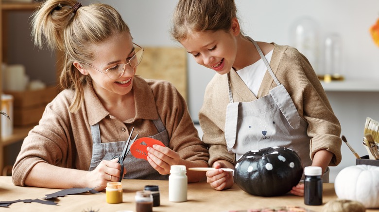 Woman and child painting pumpkin