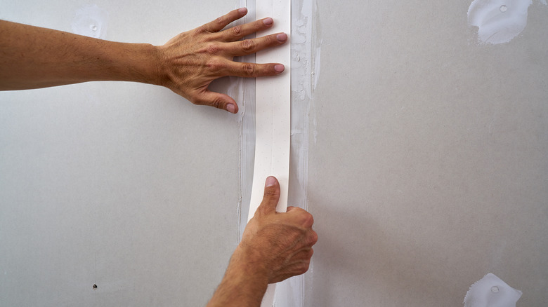 Hands taping drywall closeup