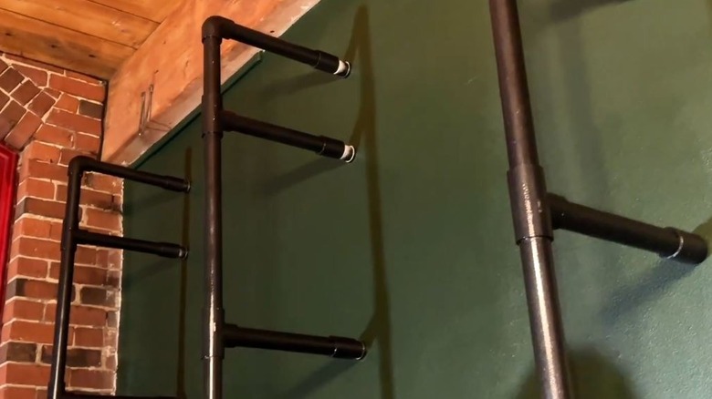 A painted PVC shelving frame is securely attached to a green wall.