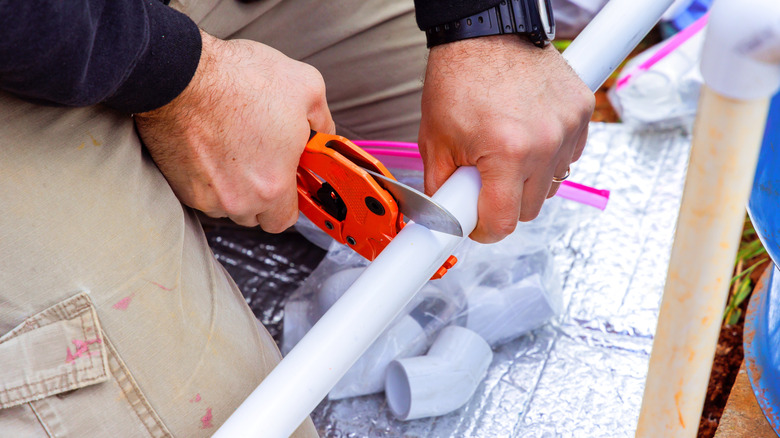 Someone cutting a PVC pipe