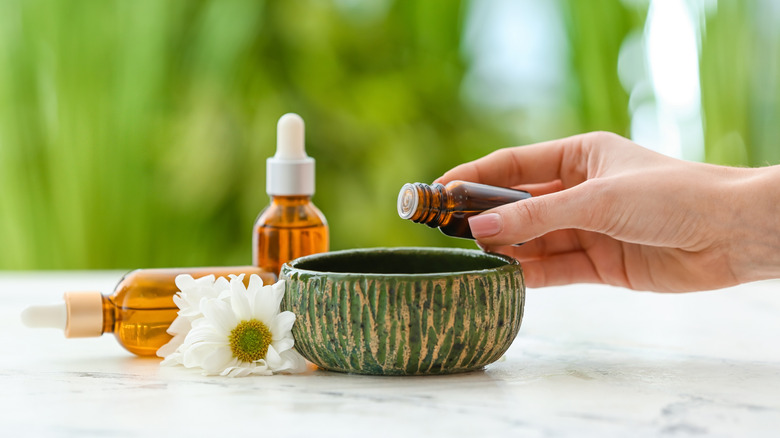 hand pouring drops of essential oil into lava rocks to diffuse in home