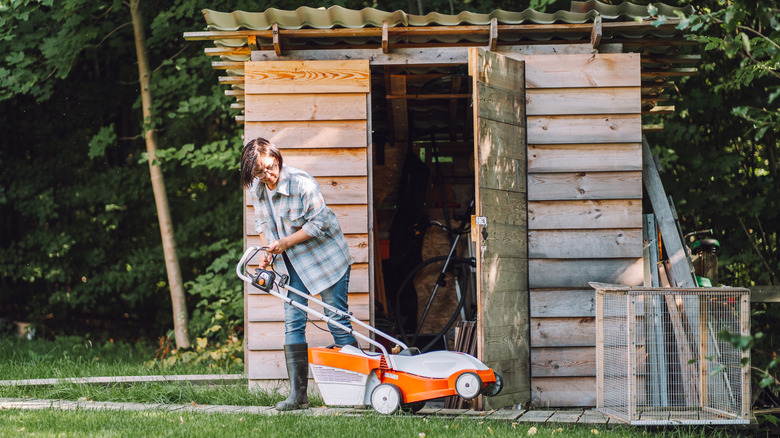 woman with mower by shed