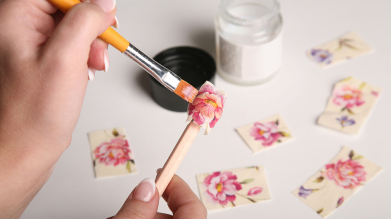 Hands applying decoupage glue to paper