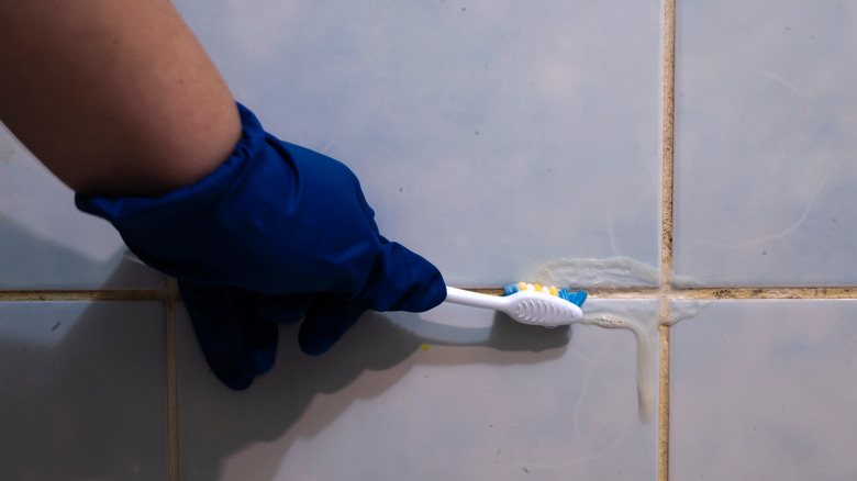 person cleaning grout with toothbrush