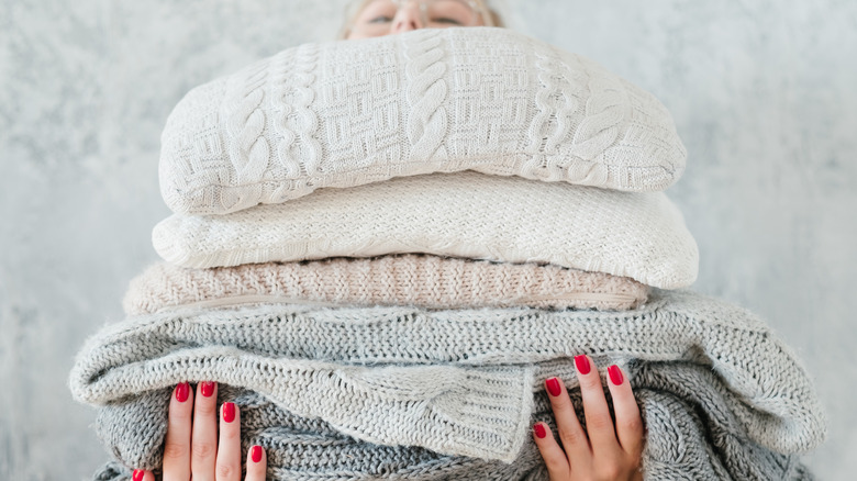 person holding stack of sweaters