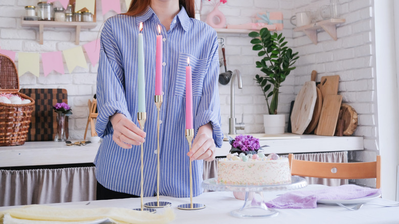 A person putting lit slender candles into candle holders for Easter