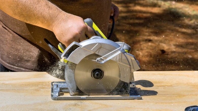 Man ripping plywood board with circular saw