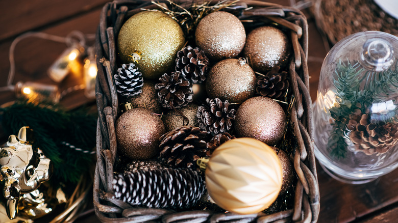 A basket filled with glittered holiday ornaments and pine cones