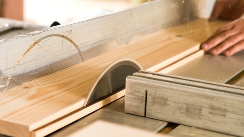 person ripping wood board with table saw