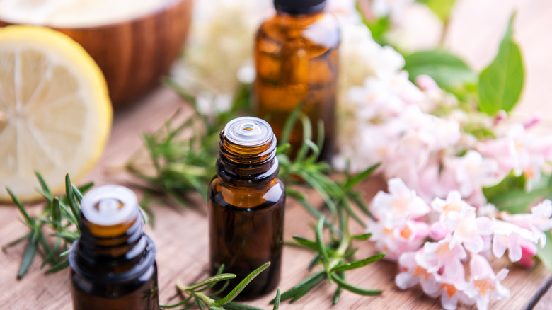 Bottles of essential oils and flowers on table