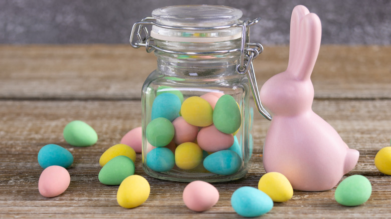 Candy jar with pastel Easter eggs inside and a pink bunny figure beside it