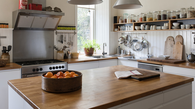 A rustic kithen with wooden countertops, shiplap walls, and open shelving