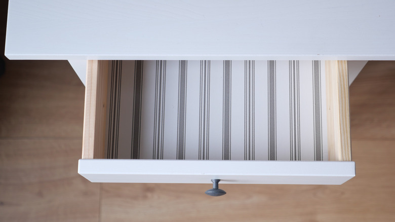 An open drawer lined with striped paper.