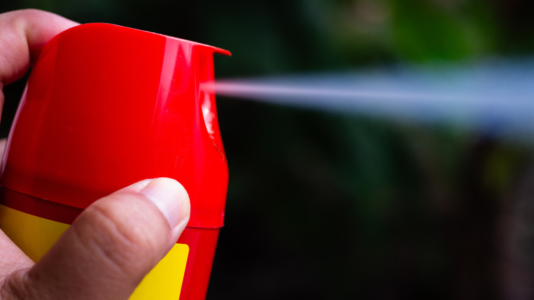 Hand spraying a red and yellow aerosol can