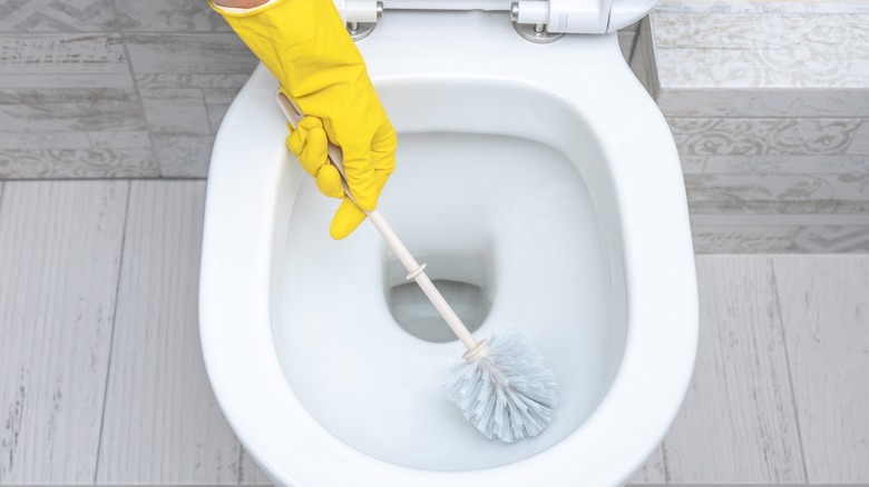 person scrubbing toilet bowl