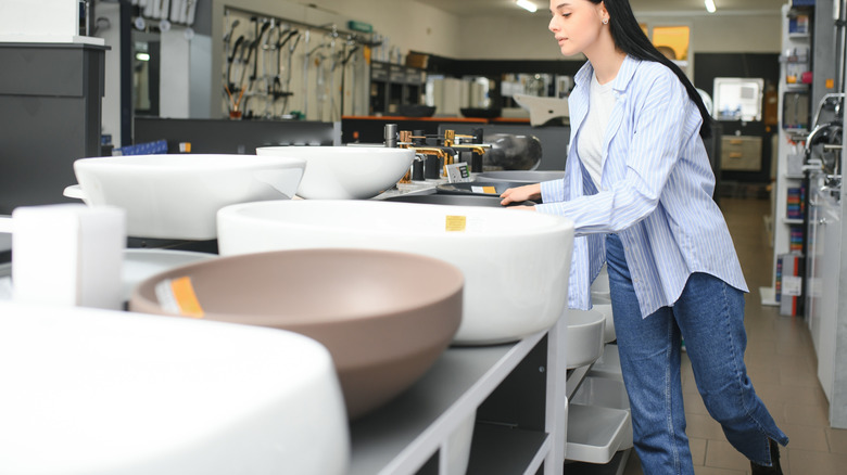 A woman looks at sinks in a store